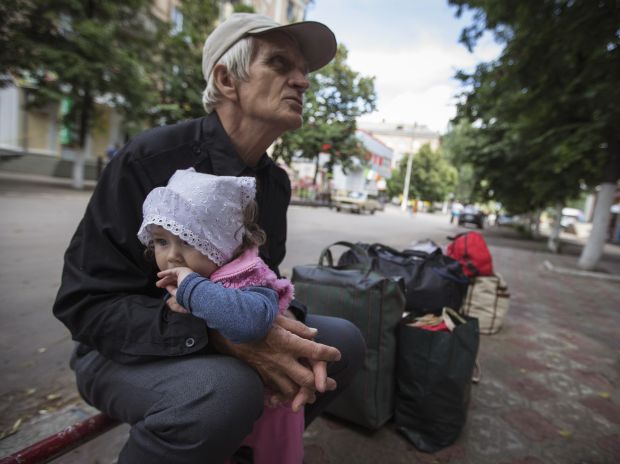 Viktor hold his granddaughter Alissa as they wait for a bus to leave Slaviansk