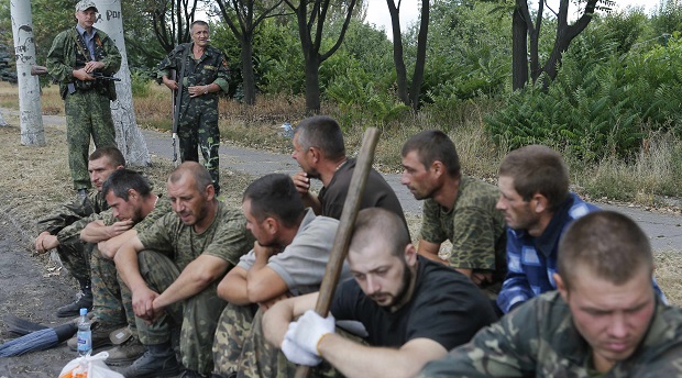 Prisoners-of-war, who are Ukrainian servicemen captured by pro-Russian separatists, sit on the ground as they are assigned to clean a street in Snizhne (Snezhnoye), Donetsk region